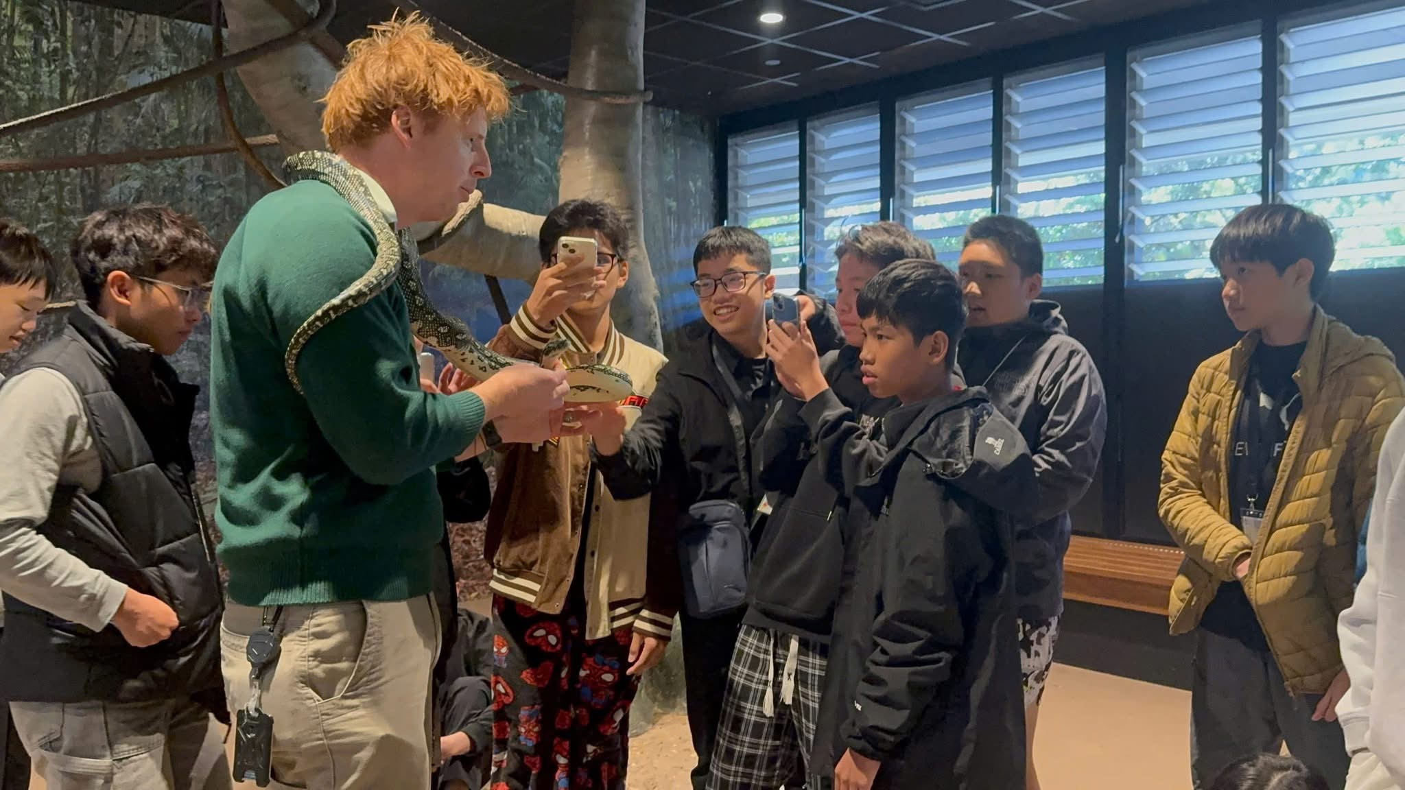 A wildlife guide showing a python to bespoke tour participants indoors